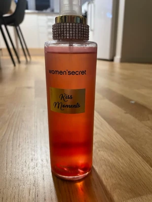 Kiss Moments Body Mist 250ml - Fräsch body mist med ungdomlig vibe från women'secret. Volym: 250 ml (8.5 fl oz). Ingredienser: Alcohol Denat., Aqua, Parfum, Propylene Glycol, Ethylhexyl Methoxycinnamate, Butyl Methoxydibenzoylmethane, Ethylhexyl Salicylate, CI 17200, CI 14700.
