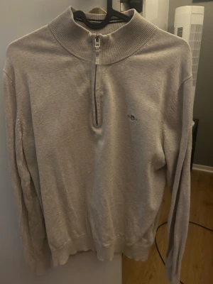 Beige half zip tröja från GANT - Snygg beige långärmad tröja från GANT med ribbad hög krage och half zip-dragkedja framtill. Diskret GANT-logga broderad på bröstet. Mjuk bomullskvalitet och klassisk passform som funkar till många stilar. Köpt för 699kr