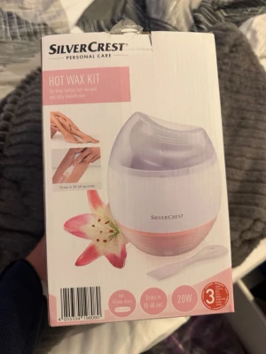 SilverCrest Hot Wax Kit hårborttagning - SilverCrest Hot Wax Kit är ett vaxkit för långvarig hårborttagning och silkeslen hud. Kitet innehåller en vaxvärmare i vit och ljusrosa plast, transparent lock och 18 vaxskivor. Medföljande spatel för enkel applicering. 20W effekt och 1,4 m sladd.