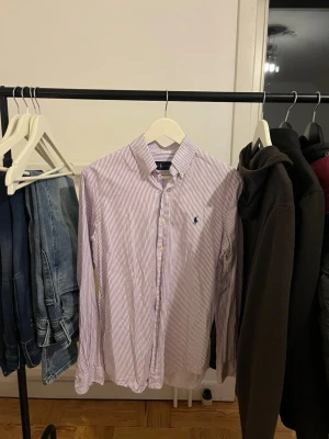 Ralph Lauren skjorta  - Tjena, säljer en vit- och lilarandig Ralph Lauren skjorta. Använd fåtal gånger och inte heller några tecken på användning. Skjortan är i storlek S men skulle säga att den kan passa M också. 