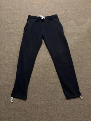 Mörkblå mjukisbyxor med snörning - Mörkblå mjukisbyxor från Russemerch i storlek S. Byxorna har elastisk midja med vit snörning, fickor fram och en bakficka. Har använts några gånger 