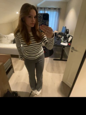 Randig offshoulder topp i bomull - Säljer en vit och svart randig offshoulder topp med lång ärm. Toppen är ribbad och har en tight passform som framhäver figuren. Perfekt för dig som gillar en stilren och trendig look. Materialet är mjukt och stretchigt bomullstyg.