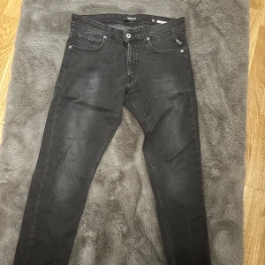 Replay Grover svarta jeans, stl 31 - Svarta Replay Grover jeans i klassisk femficksmodell med snygga slitningar och diskreta detaljer. Jeansen har rak passform och är tillverkade i mjukt jeansmaterial med en mörk tvätt. Perfekta för dig som gillar stilrena och coola jeans.