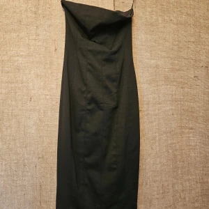 Svart axelbandslös klänning - Elegant svart axelbandslös klänning i lång modell. Perfekt för en stilren look med enkel design och smickrande passform.