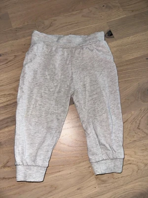 Ljusgrå mjukisbyxor med resår Gråa byxor - Säljer ett par ljusgrå mjukisbyxor med resår i midjan och vid bensluten. Byxorna är tillverkade i mjukt bomullsmaterial och har en enkel, avslappnad passform. Perfekta för chill dagar eller när du vill vara extra bekväm.Ljusgrå mjukisbyxor med resår Gråa byxor