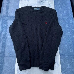 Svart kabelstickad tröja Polo Ralph Lauren - Väldigt skön svart kabelstickad tröja från Polo Ralph Lauren med klassisk röd broderad logga på bröstet. Hör av er vid frågor 💬 