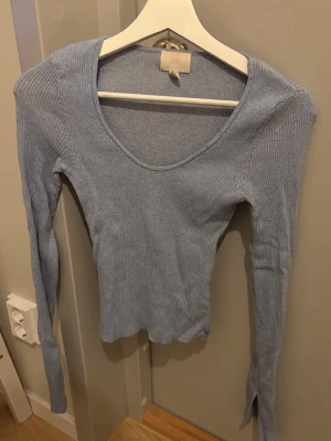 Ljusblå ribbad långärmad topp H&M - Säljer en ljusblå långärmad topp från H&M med ribbad struktur och rundad halsringning. Toppen är slim fit och har en mjuk, stretchig känsla som gör den skön att bära🫧