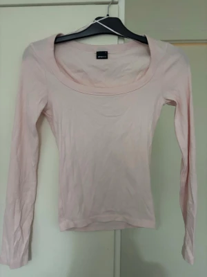 Ljusrosa långärmad topp Gina Tricot - Säljer en ljusrosa långärmad topp från Gina Tricot med rundad halsringning. Toppen är slim fit och tillverkad i mjuk bomull, perfekt att styla med jeans eller kjol. Enkel och stilren design som funkar året runt.