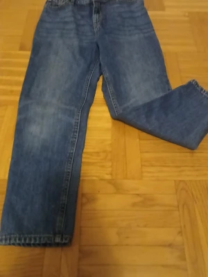 Blå jeans från Lindex Detroit - Säljer ett par klassiska blå jeans från Lindex Detroit med raka ben och normal passform. Jeansen har fem fickor, gylf med knapp och dragkedja samt snygga kontrastsömmar. Perfekta för dig som gillar enkel och tidlös stil.