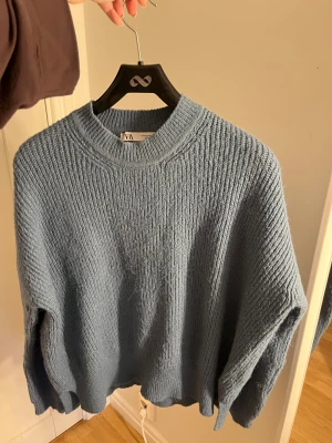 Blå stickad tröja från ZARA - Säljer en blå stickad tröja från ZARA i storlek M. Tröjan har en rund halsringning och är ribbstickad med lång ärm. 