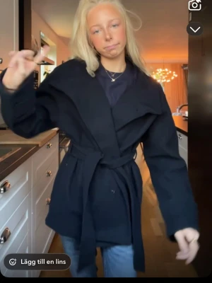 Marinblå omlottjacka med bälte - Snygg mörkblå kappa ifrån Gina tricot Young, kappan är just nu slutsåld i alla storlekar på hemsidan och nypris är 449kr  kappan går att användas såsom på bilden eller att man knäpper en knapp så att det blir en krage på. Det är storlek 158/164 och den är i väldigt bra skick ❤️😊