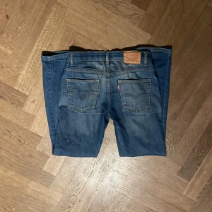 Levi's 511 blå jeans - Säljer ett par Levi's 511 jeans i klassisk blå tvätt med snygga slitningar. Modellen har smal passform och raka ben, fem fickor och knappgylf. Ikonisk Levi's-lapp bak i midjan och röd etikett på bakfickan. Perfekta för en chill och stilren look.
