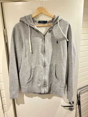 Ralph Lauren  - En grå Ralph Lauren zip hoodie storlek M | väldigt bra skick | äkta med qr kod | liten defekt på armen men syns knappt se bild 7 | pris går att diskutera vid snabb och enkel affär |