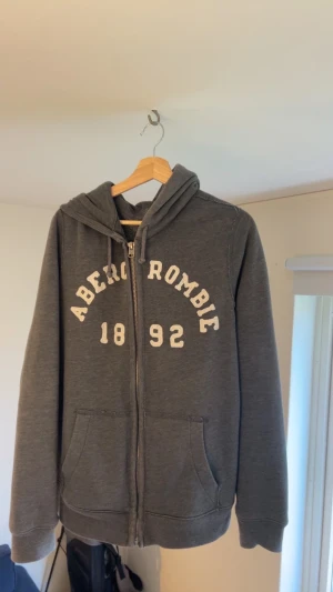 Grå Abercombie & Fitch zip up hopdie - Fet mörk grå Abercombie & fitch zip up hoodie. Bra skick och dragkedja funkar felfritt.