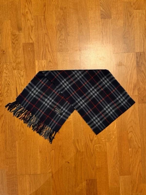 Mörkblå Burberry halsduk - Säljer en mörkblå halsduk från Burberry. Halsduken är gjord i lamull och är i gott skick. Var inte rädd för frågor. Pris diskuteras inte!