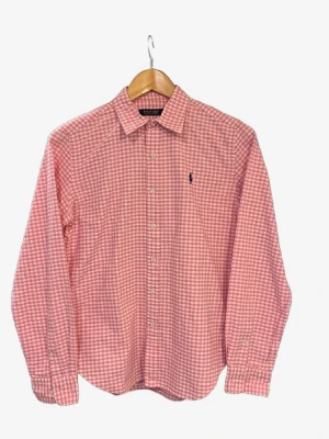 Rutig rosa skjorta från Polo Golf - Säljer en snygg rutig skjorta från Polo Golf Ralph Lauren i rosa och vitt. Skjortan har klassisk krage, långa ärmar och knappar hela vägen. Materialet är mjuk bomull och den har den ikoniska Polo-loggan broderad på bröstet. Perfekt för dig som gillar stilrena och fräscha plagg.