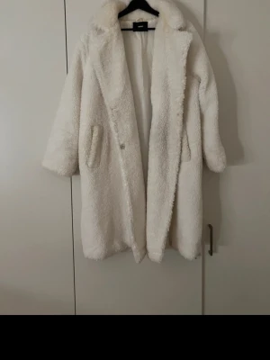 Vit teddyjacka från bikbok  - Säljer en fluffig och oversized vit teddyjacka från bikbok . Jackan har bred krage, två sidofickor och stängs med knapp framtill. Perfekt för dig som vill ha en mysig och trendig look under kyliga dagar.