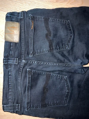 Nudie Jeans - Säljer ett par svarta jeans från Nudie Jeans. Dem har en lite touch utav blå i färgen som jag tycker är riktig snyggt. Nästan aldrig använda och är i superbra skick😁 W27 L32 skriv vid mer frågor
