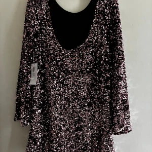 Rosa paljettklänning från BIANCO - Säljer en loose rosa paljettklänning från Gina i storlek S. Klänningen har en kort, rak passform med långa ärmar och är täckt av glittriga paljetter som ger en riktigt festlig vibe. Rund halsringning och mjukt innerfoder för extra komfort.