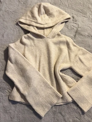 Beige stickad hoodie - Mysig beige stickad hoodie med breda ribbade muddar vid ärmslut och nederkant. Tröjan har en stor huva och är långärmad med loose passform. Perfekt för chill dagar och när du vill ha det extra bekvämt. Aldrig använd!
