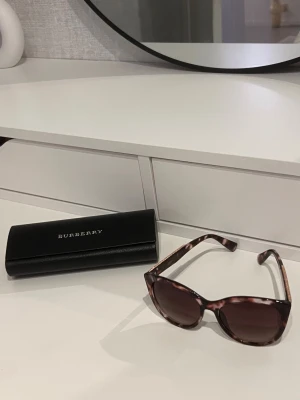 Solglasögon + Fodral - Ett par mörk bruna snygga tiger pattern solglasögon från Glitter med en äkta original fodral båda i mycket bra skick och helt utan defekter eller märken (glasögonen är annorlunda märke än fodralen) 