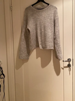Grå stickad tröja från Gina Tricot - Mysig grå stickad tröja från Gina Tricot i storlek 170. Tröjan har en enkel design med rund hals och långa ärmar. Perfekt för att hålla sig varm under kyliga dagar och passar till många olika stilar.