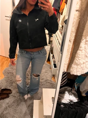 Svart kofta Puma x BMW - Svart kofta från Puma i samarbete med BMW. Jackan har en croppad passform, dragkedja framtill, högt krage och två sidofickor. Puma-logga och BMW-emblem på bröstet 