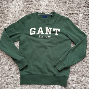 Grön sweatshirt från GANT - Snygg grön sweatshirt från GANT med vit broderad logga och texten 'Est. 1949' på bröstet. 