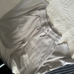 Beige mjukisbyxor från 157, storlek S - Säljer ett par beige mjukisbyxor från 157 i storlek S. Byxorna har bred resår i midjan med snörning och stora fickor framtill. Perfekta för chill dagar eller när du vill vara extra bekväm. Materialet är mjukt och skönt mot huden.