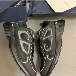 Svarta Dior sneakers med vita detaljer - Säljer ett par svarta Dior sneakers med vita kontrastsömmar och CD-logga bak. Skorna har en chunky sula, snörning och meshpaneler för extra andningsförmåga. Snygg design med både skinn och textilmaterial, perfekta för dig som gillar exklusiva och trendiga sneakers.