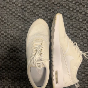 Vita Nike air Max thea sneakers med Air-sula - Snygga vita Nike sneakers med klassisk swoosh-logga på sidan. Ovandelen är i mesh och syntet för en luftig känsla, och sulan har synlig Air-dämpning. Skorna har snörning och en sportig, modern look som passar till det mesta. Används 1-2 ggr ny skicka hör av er vid fundering!🙌