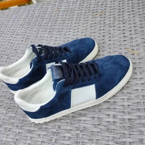 Valentino flycrews blå mockasneakers - Snygga Valentino flycrews sneakers i blå mocka och vitt skinn. Skorna har svarta snören, vita detaljer och coola nitar bak på hälen. Yttersulan har ett unikt camouflagemönster i grönt och svart. Perfekta för dig som vill sticka ut med stil.