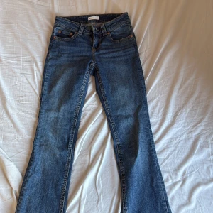 Blåa low waist bootcut jeans - Snygga blåa low waist bootcut jeans från Gina Tricot med bakfickor med lock och knapp. De är i storlek 34 och säljer de för att de var för stora❤️ 