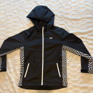 Vans Vindjacka - Svart vindjacka från Vans i storlek barnstorlek L, Den är S i vanlig storlek. Jackan är sparsamt använt och i fint skick med snyggt schackrutigt tema ♟️den är regntålig