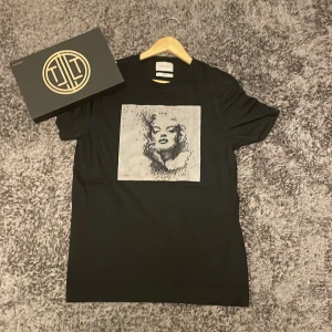 Svart t-shirt Limitato med konstmotiv - Snygg svart t-shirt från Limitato med ett stort fyrkantigt konstmotiv i grått och svart på bröstet. T-shirten har klassisk passform och rund hals. Perfekt för dig som vill sticka ut med en unik design och coolt print.