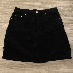 Svart manchesterkjol med fickor - Säljer en svart kortkjol. Kjolen passar perfekt för dig som gillar en stilren och enkel look! Lätt att matcha med både sneakers och boots.