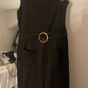 Svart jumpsuit med bälte och vida ben - Svart one shoulder jumpsuit, använd endast 1 gång 