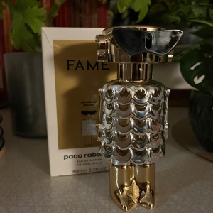 Paco Rabanne Fame EdP 80ml - Unik parfymflaska från Paco Rabanne i form av en futuristisk robot. Flaskan är i guld- och silverfärgad metall med svarta solglasögon som detalj. Rymmer 80 ml Eau de Parfum och är riktigt snygg att ha framme på hyllan.