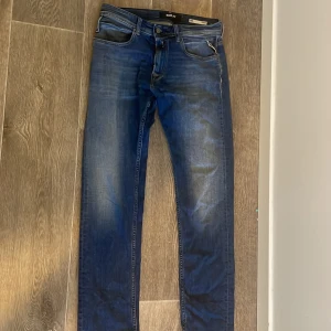 Blå Replay jeans, midwaist, straight fit - Säljer ett par klassiska blå jeans från Replay med snygg tvätt och raka ben. Jeansen har fem fickor, normal passform och midwaist. Tillverkade i jeansmaterial och har Replay-logga bak på linningen. Perfekta till din vardagsstil.
