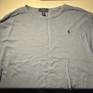 Ljusblå långärmad tröja Polo Ralph Lauren - Ljusblå långärmad tröja från Polo Ralph Lauren i mjuk bomull. Klassisk rund halsringning och ikoniska broderade loggan på bröstet. Perfekt för en avslappnad och stilren look. Storlek barn XL, passar S💫