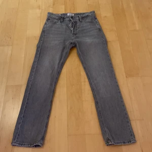 Grå jeans från Jack & Jones - Snygga grå jeans från Jack & Jones. Jeansen har passformen relaxed med knappgylf. Perfekta för dig som gillar en clean look. Skriv frågor och ge prisförslag. Storlek 27/30.