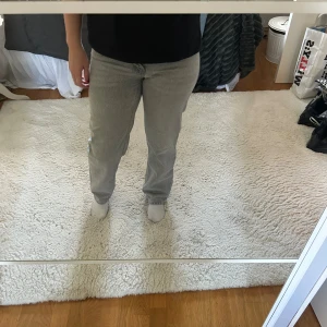 Grå raka jeans i straight fit - Säljer ett par ljusgrå jeans med rak passform och klassisk femficksdesign. Jeansen har normal midja och är tillverkade i ett mjukt bomullstyg. 