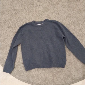 Blå stickad tröja från 157 - Enkel och snygg blå stickad tröja från 157. Tröjan har rund halsringning, ribbade muddar och lång ärm. Perfekt för lager-på-lager och chill dagar. Passar dig som gillar basic och stilrent.
