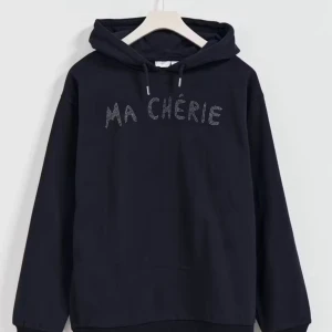 Svart hoodie med strass Ma Chérie - Svart hoodie med huva och snörning, dekorerad med texten 'MA CHÉRIE' i strass framtill. Tröjan har en avslappnad passform och långa ärmar, perfekt för en cool och bekväm stil.