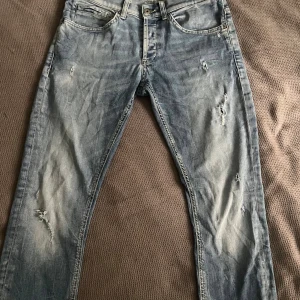 Ljusblå skinny jeans från Dondup - Säljer ett par ljusblå skinny jeans från Dondup med slitna detaljer och snygg tvätt. Jeansen har klassisk femficksdesign, orangea sömmar och är tillverkade i bomull. Perfekt för dig som gillar en avslappnad men trendig look.