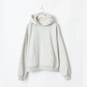 Grå hoodie från Gina Tricot - En klassisk ljusgrå hoodie från Gina Tricot med huva. Tröjan har ribbade muddar vid ärmslut och nederkant, och tillverkad i mjuk bomullsblandning.