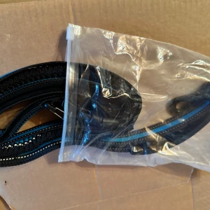 Svart och blått bälte koppel med krokspänne för husdjur  - Säljer ett svart bälte med blå rand och reflexdetaljer. Bältet är gjort i slitstark syntet och har ett smidigt krokspänne i plast. Perfekt för dig som har husdjur ❤️katt eller hund 