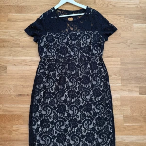 Säljer Mörkblå Klänning Dorothy Perkins! - Klänningen är som helt ny och endast använd ett fåtal gånger. Storlek: 46 Supersnygg mörkblå spetsklänning från Dorothy Perkins med korta ärmar och rund hals. Klänningen har ett vackert blommigt spetsmönster och en ljus underklänning som ger en fin kontrast. Dragkedja i sidan och liten öppning bak i nacken.