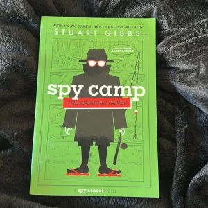 Spy Camp: The Graphic Novel - Följ med på ett actionfyllt äventyr på spionläger! Ben Ripley måste överleva faror, fiender och galna utmaningar i denna färgstarka och spännande grafiska roman. Perfekt för dig som gillar mysterier, humor och coola spioner.