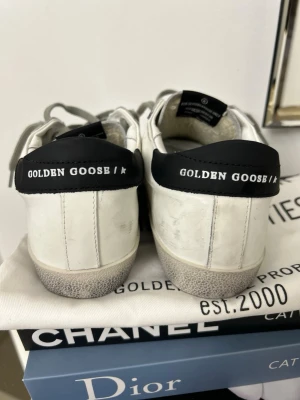 Golden Goose vita sneakers med svart stjärna - Tja! Säljer ett par golden goose dam skor i storlek 38. Riktigt  snygga skor som hållts i fint skick. Säljer för rimligt pris- kan diskuteras vid snabb affär. Kvitto, box och goodie bag tillkommer. Dma💥